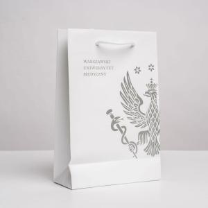 Biała prostokątna torba papierowa z białymi rączkami. Na torbie szary/srebrny logotyp WUM.