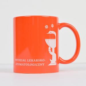 Kubek o klasycznym prostym kształcie w kolorze jasnoczerwonym z logotypem i nazwą Wydziału Lekarsko-Stomatologicznego w kolorze białym